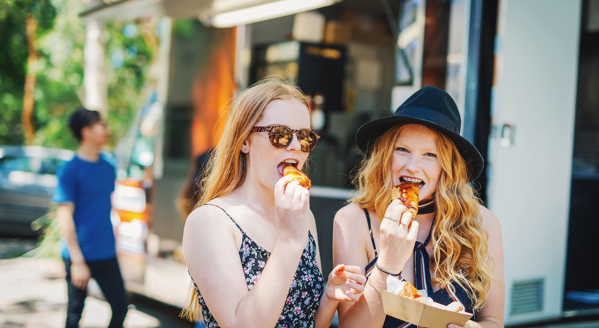 two girls enjoying their food at a food truck festival