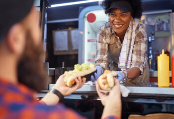 food truck employee giving two sandwiches to a male customer