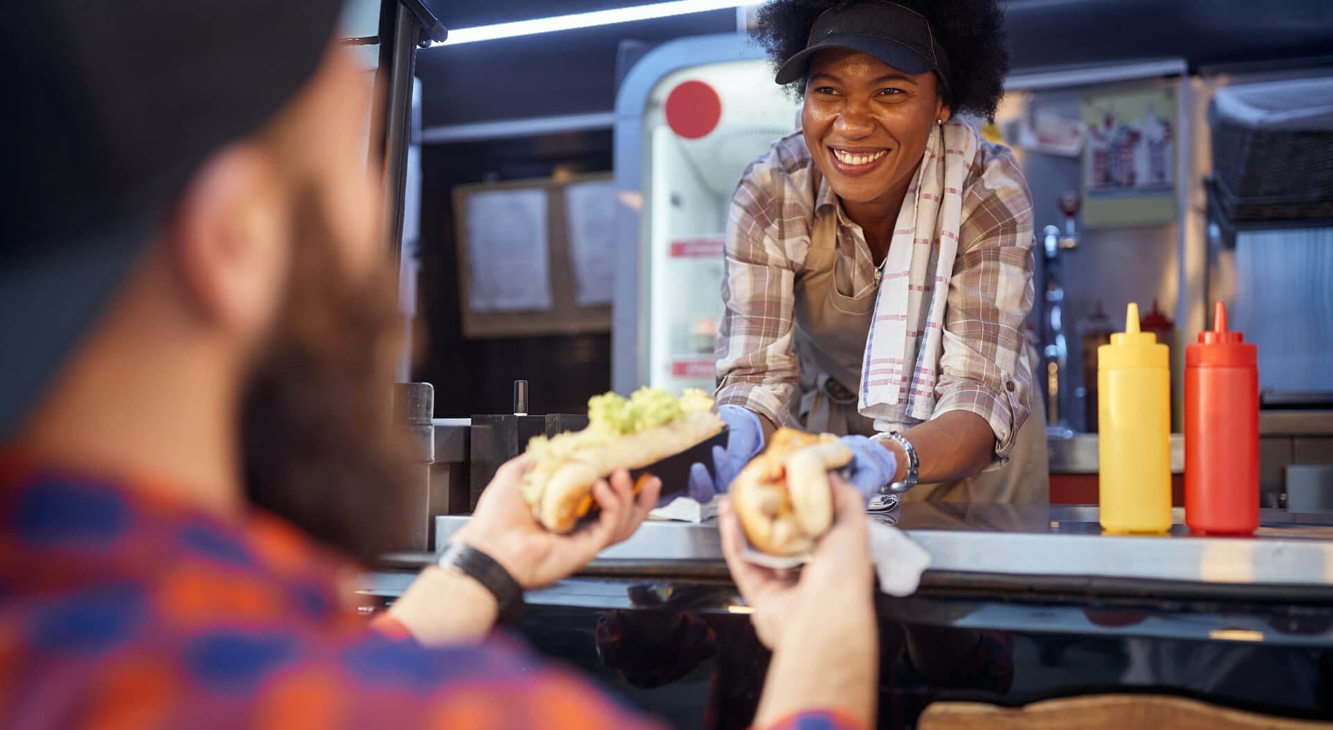 food truck employee giving two sandwiches to a male customer