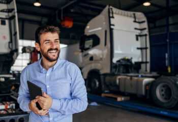 smiling truck owner standing in auto park and holding tablet
