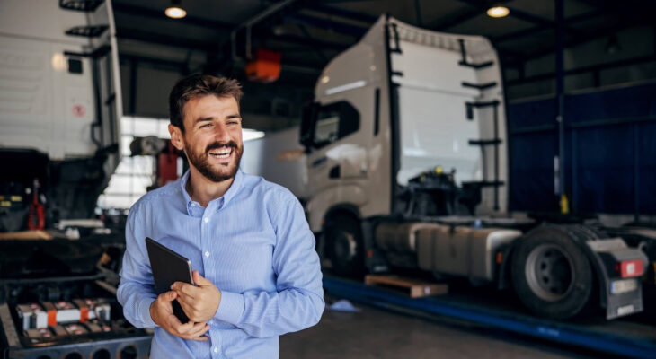 smiling truck owner standing in auto park and holding tablet