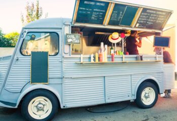 teal colored food truck selling with a written menu board