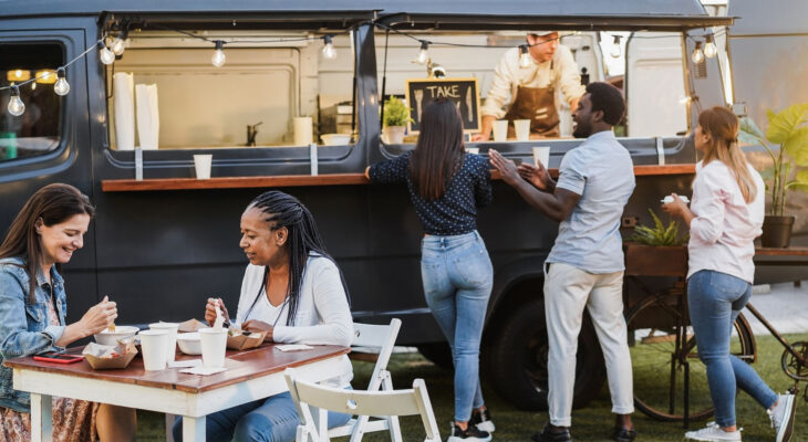 group of people ordering and eating food from a food truck