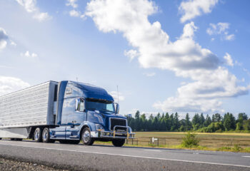 blue semi truck driving on a sunny day