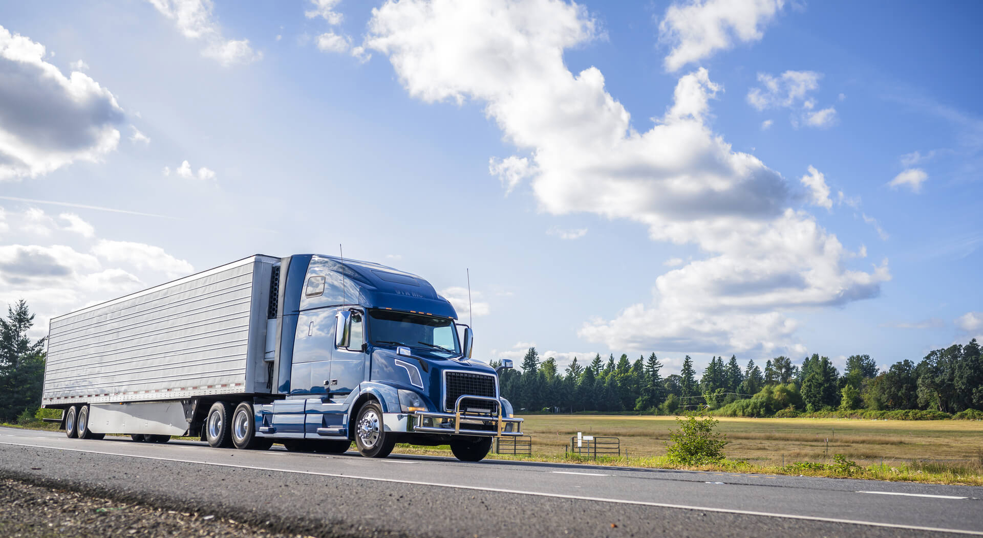 blue semi truck driving on a sunny day